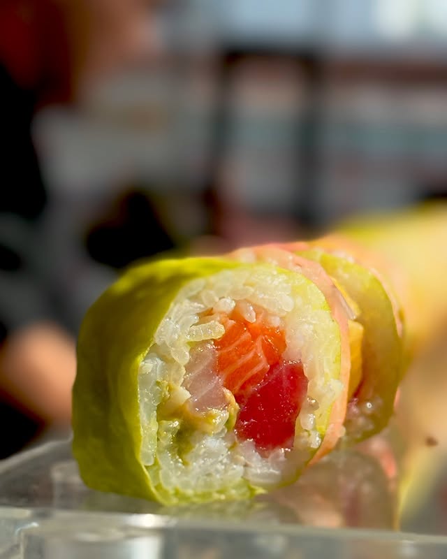 Sushi chef preparing a colorful rainbow roll at a live station during a New York event